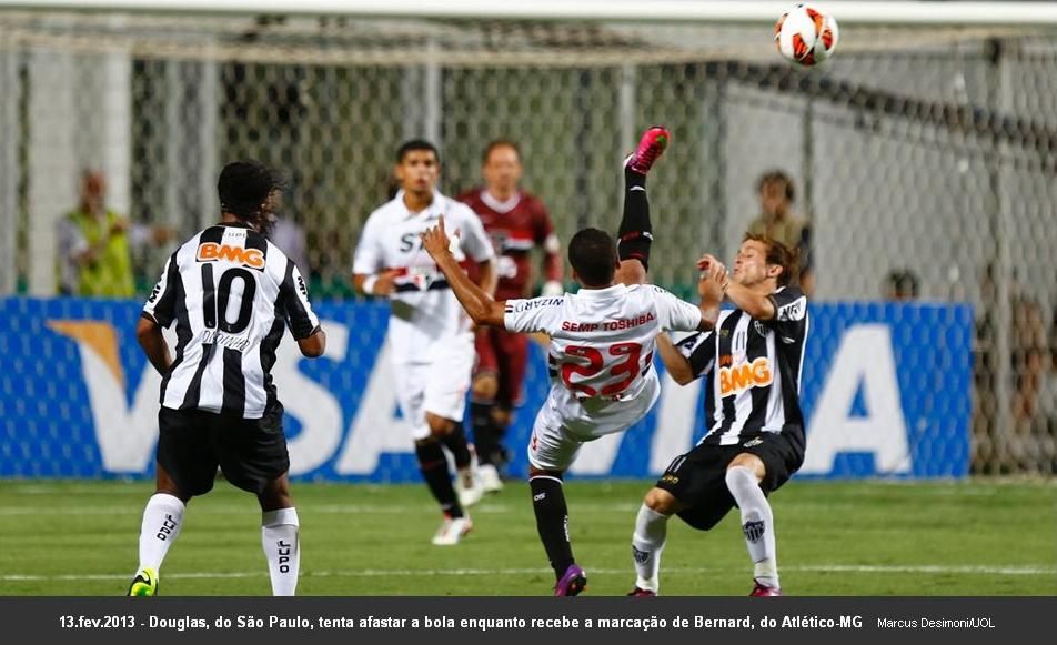 Douglas, do São Paulo, tenta afastar a bola enquanto recebe a marcação de Bernard, link da matéria: http://fotos.noticias.bol.uol.com.br/esporte/2013/02/13/atletico-mg-e-sao-paulo-duelam-na-libertadores.htm#fotoNav=46